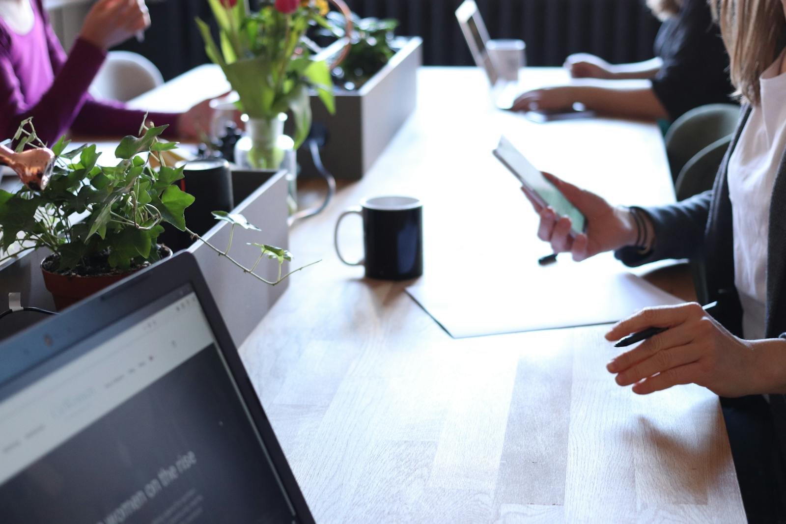 Contemporary office environment featuring teamwork with laptops, coffee, and greenery. General Liability